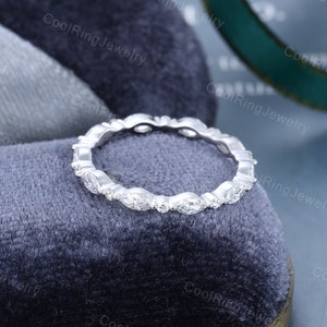 May include: A delicate eternity band ring with a row of marquise-shaped diamonds set in a white metal band.