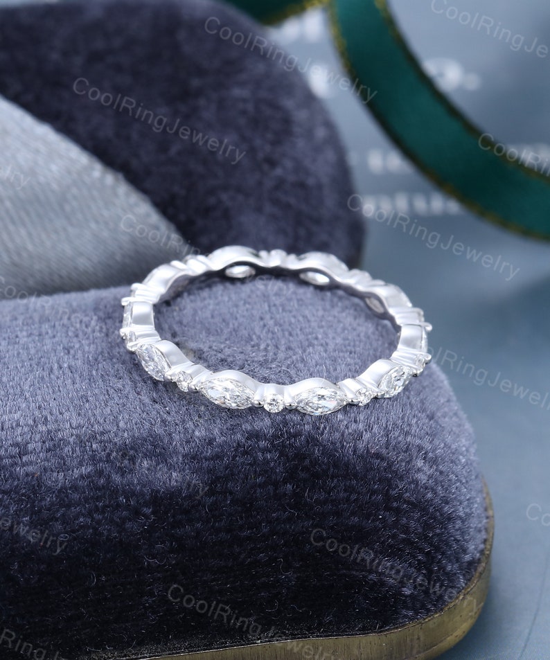 May include: A delicate eternity band ring with a row of marquise-shaped diamonds set in a white metal band.
