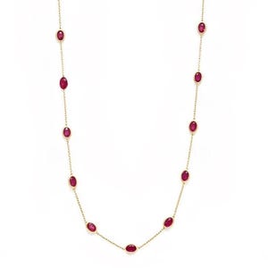 Può includere: Una lunga collana a catena dorata con rubini rossi ovali incastonati a lunetta e distanziati uniformemente. I delicati anelli dorati collegano ogni gemma in un design a stazioni continuo, creando un gioiello raffinato ed elegante.
