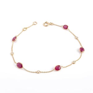 Può includere: Un delicato bracciale a catena in oro con un'alternanza di rubini rosa scuro taglio ovale e piccole pietre rotonde trasparenti incastonate a lunetta. Il bracciale include una chiusura a molla circolare e una breve catenella di estensione.