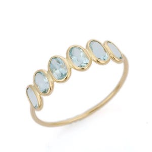 May include: A gold ring with six oval-shaped aquamarine gemstones set in a bezel setting.