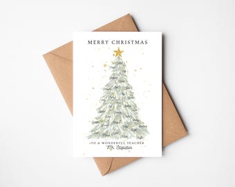 以下が含まれることがあります： クリスマスカード。水彩画のクリスマスツリーのイラストで、名前と金色の星で飾られています。カードには「素晴らしい先生にメリークリスマス」と書かれています。カードは茶色の封筒の上にあります。