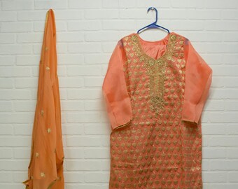 May include: A peach-colored long-sleeved dress with gold embroidery and a matching peach-colored scarf.