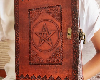 May include: A brown leather journal with a pentagram design and a metal clasp. The journal has intricate embossed details around the edges.
