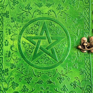 May include: Green leather journal with a pentacle design embossed on the front cover. The cover has a Celtic knot border and a brass clasp.