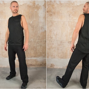 Może przedstawiać: Czarna koszulka bez rękawów z pionowym wzorem na plecach. Koszulkę nosi osoba w czarnych spodniach.