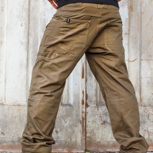 May include: A pair of brown cargo pants with multiple pockets and a zipper detail on the leg. The pants are made of a durable, cotton-blend fabric.