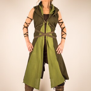 May include: A green and brown hooded tunic with a long, flowing skirt and a brown leather belt. The tunic is tied at the waist with a brown leather cord. The person is wearing brown leather boots.