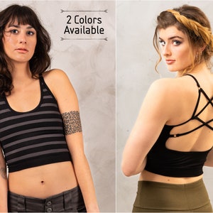 May include: Two women wearing black tank tops with different back designs. The tank top on the left has black and gray stripes. The tank top on the right has a criss-cross design on the back. "2 Colors Available" is written in the top right corner of the image.