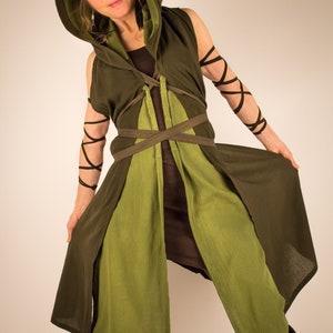 May include: A green hooded tunic with brown straps and a brown undergarment. The tunic has a long, flowing design and is tied at the waist with a brown belt.