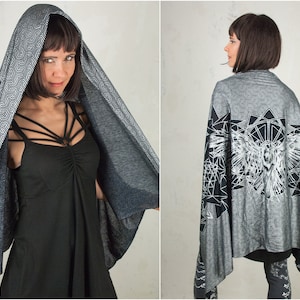 May include: A black and white geometric patterned scarf with an owl design. The scarf is draped over a person's shoulders.