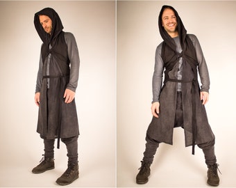 May include: A person wearing a long black hooded garment with a black vest and grey pants. The garment has a long, flowing skirt and a belt.