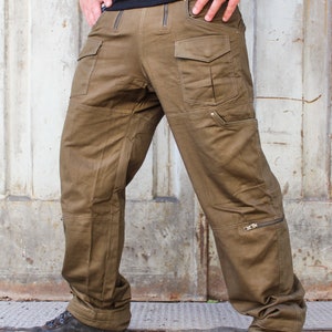 May include: A pair of brown cargo pants with multiple pockets and zippered details. The pants have a relaxed fit and are made of a durable fabric.