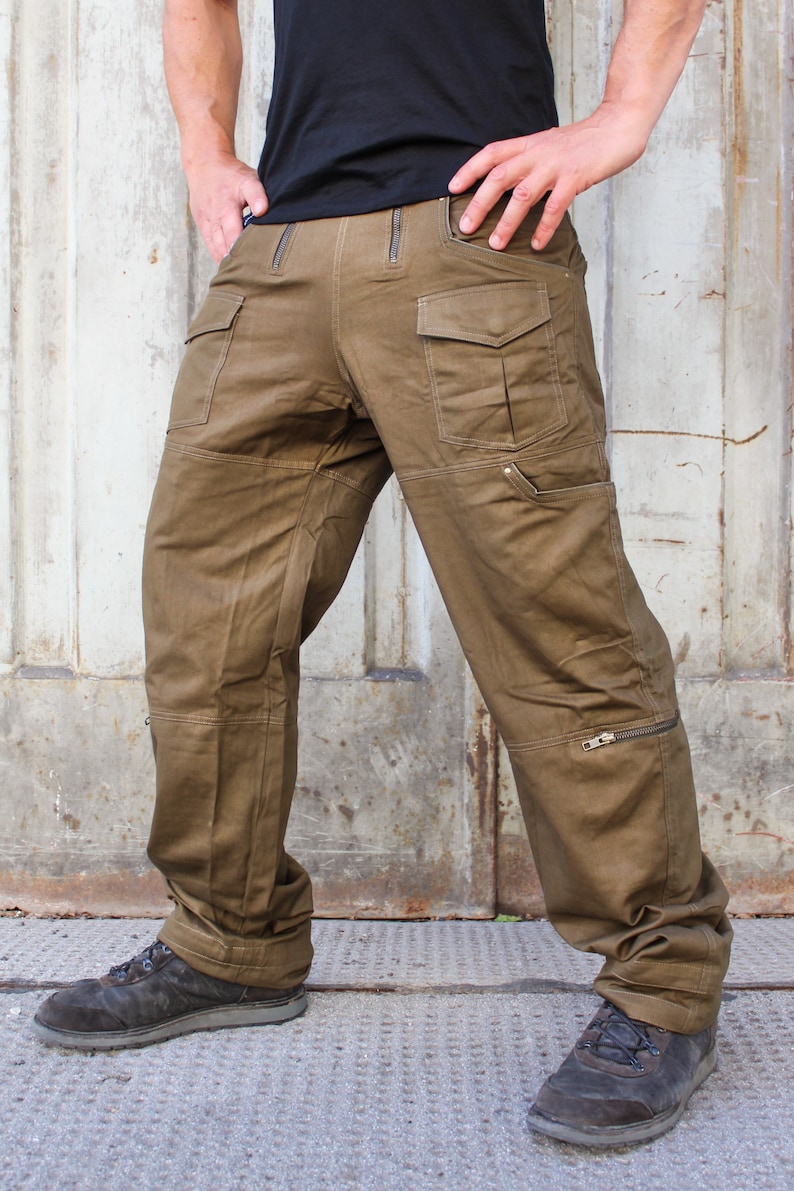 May include: A pair of brown cargo pants with multiple pockets and zippered details. The pants have a relaxed fit and are made of a durable fabric.