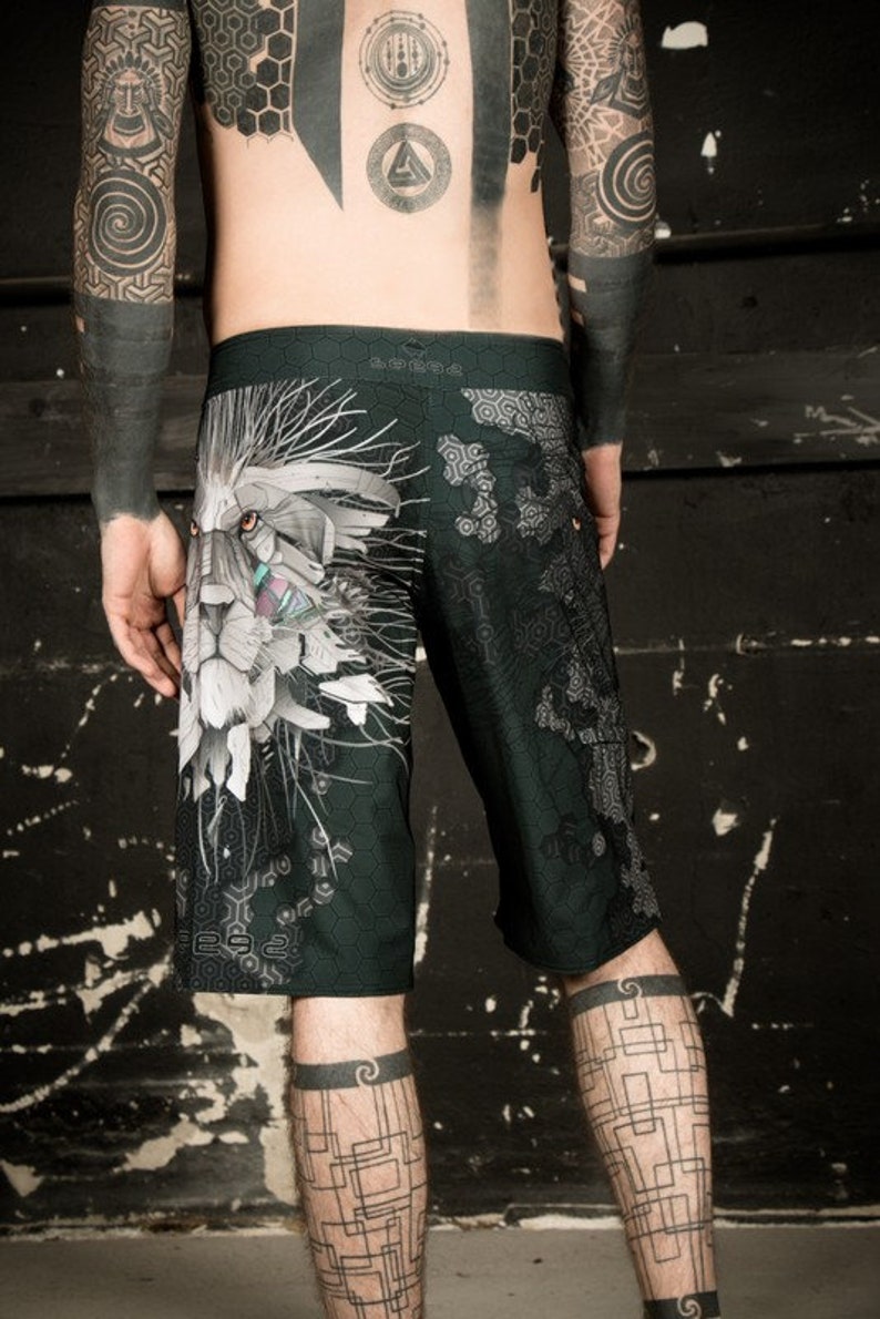 May include: Black and white patterned swim trunks with a graphic print of a lion's face. The trunks have a geometric pattern and the lion's face is stylized with a futuristic design.