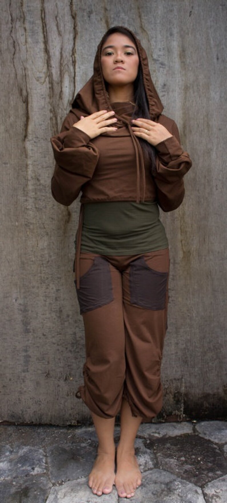 May include: A woman wearing a brown hooded top with a drawstring and matching brown pants. The pants have large pockets on the front.