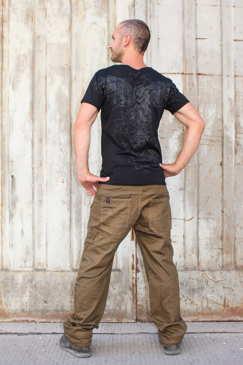 May include: A black t-shirt with a graphic print of an owl and geometric shapes on the back. The person is wearing brown cargo pants.