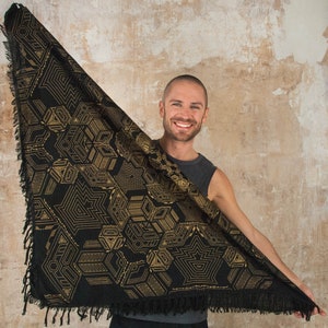 May include: A black triangular scarf with a gold geometric pattern. The scarf has a fringed edge.