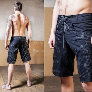 Puede incluir: Bañador negro con estampado geométrico. El bañador tiene cintura con cordón y un bolsillo lateral.