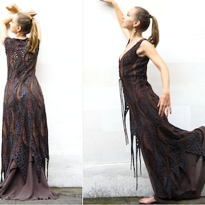 Könnte beinhalten: Ein langes, braunes und schwarzes Kleid mit einem fließenden, geschichteten Rock und einem spitzem Muster. Das Kleid ist ärmellos und hat einen V-Ausschnitt.