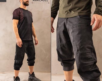 May include: Black cargo pants with multiple pockets and a zipper detail. The pants are cropped and have a cuffed hem.