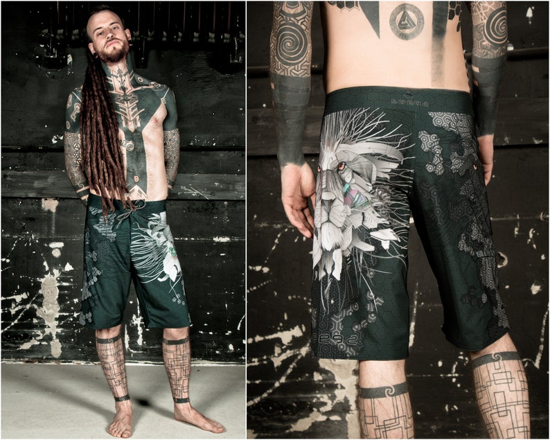 May include: Black and white patterned swim trunks with a lion graphic. The lion's face is white with black and red details. The background of the trunks is black with a geometric pattern.