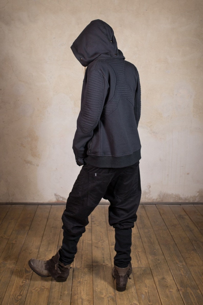 May include: A black hooded sweatshirt with a zipper closure and quilted detailing on the back. The sweatshirt is worn with black pants.