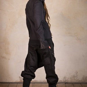 May include: A black hooded sweatshirt with zippered pockets and a black pair of pants. The person is wearing brown boots.