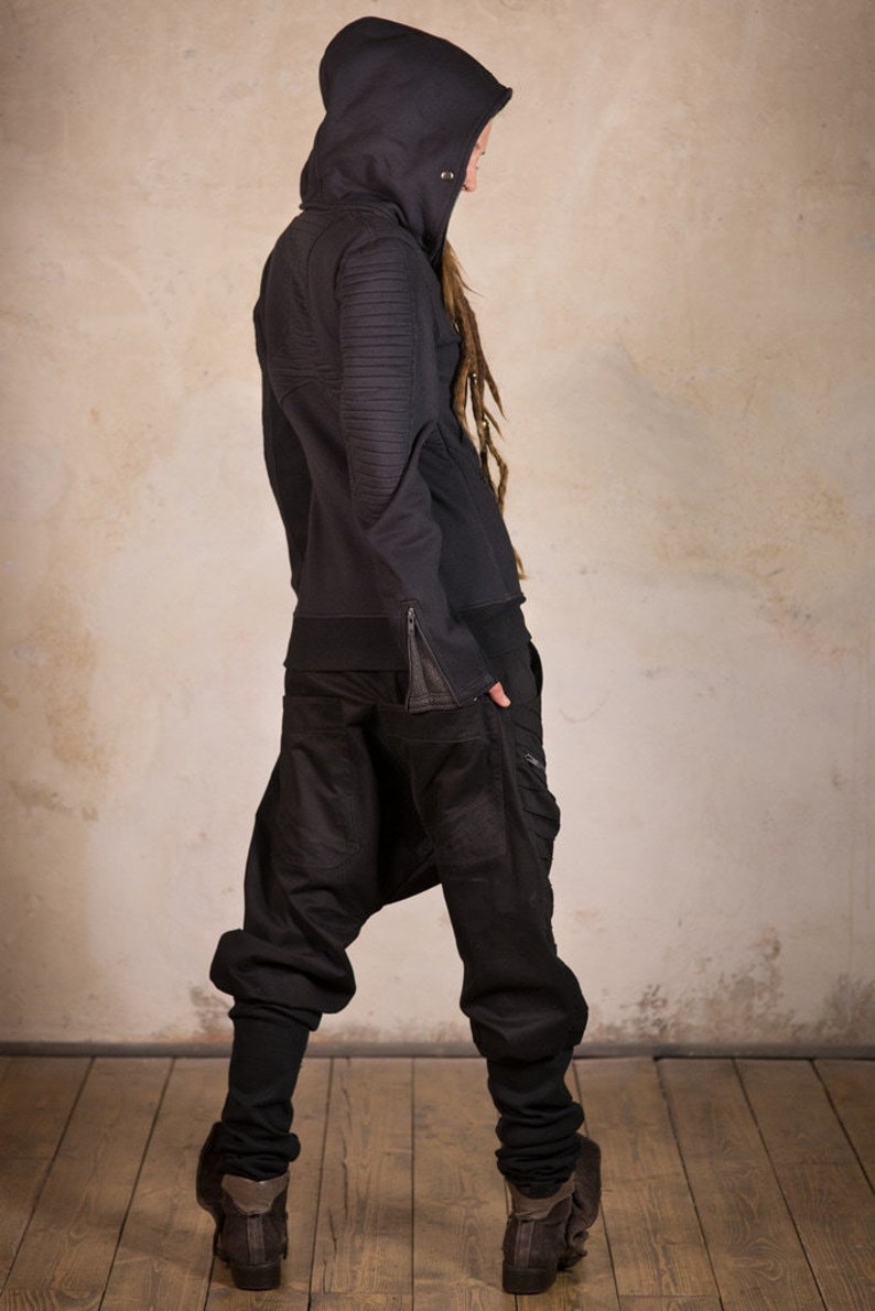 May include: A black hooded sweatshirt with zippered pockets and a black pair of pants. The person is wearing brown boots.