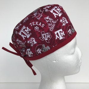 May include: A maroon scrub hat with a white print of the Texas A&M logo and the words "Gig 'Em" and "Texas A&M".