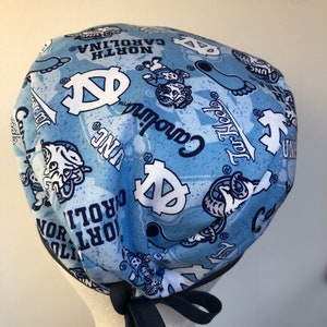 May include: A blue and white patterned surgical scrub hat with a navy blue tie. The hat features the University of North Carolina Tar Heels logo and mascot, Rameses.