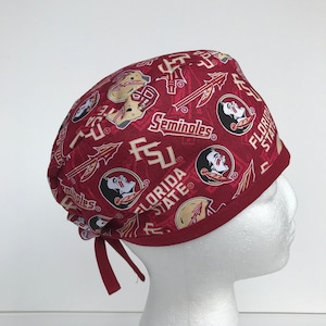 May include: Red scrub hat with a pattern of Florida State Seminoles logos, including the Seminole head logo, the FSU logo, and the words "Florida State" and "Seminoles".
