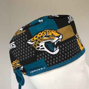 May include: A teal, black, gold and white patterned surgical scrub hat with a jaguar graphic and the text "JACKSONVILLE JAGUARS".