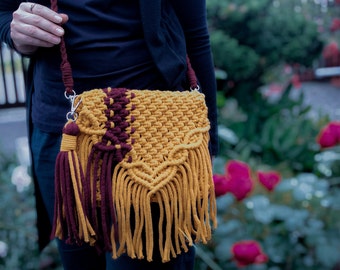 May include: A mustard yellow and burgundy crocheted crossbody bag with long fringe tassels.