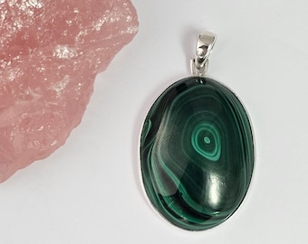 May include: Oval-shaped malachite pendant with a silver bail. The malachite is a deep green with swirling patterns.