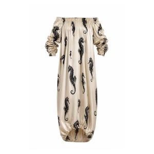 May include: Off-the-shoulder maxi dress in a cream color, adorned with a repeating pattern of black seahorse illustrations. The dress features long sleeves with gathered cuffs and a relaxed, flowing silhouette.