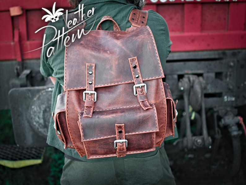 May include: A brown leather backpack with multiple buckles and pockets. The backpack has a distressed look and is made of high-quality leather.