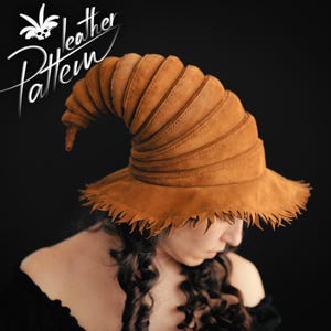 May include: A brown leather hat with a tall, pointed crown and a wide brim. The crown is made of multiple layers of leather, creating a textured look. The brim has a fringed edge.