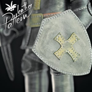 Puede incluir: Primer plano de un escudo y armadura de caballero medieval. El escudo es gris con un dise&ntilde;o de cruz amarilla y costuras blancas. La imagen incluye el texto "Leather Pattern".