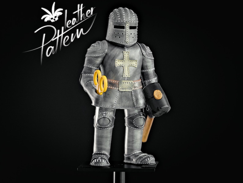 Puede incluir: Figura de caballero de cuero gris hecha a mano con casco, tijeras amarillas y un martillo negro. El caballero tiene una cruz blanca en el pecho y un cintur&oacute;n decorativo. Las palabras "leather Pattern" est&aacute;n en la esquina superior izquierda.
