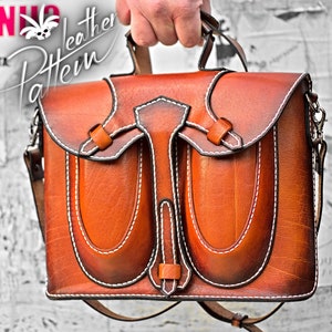 May include: A brown leather satchel bag with two front pockets and a white stitch detail. The bag has a top handle and a long adjustable shoulder strap.