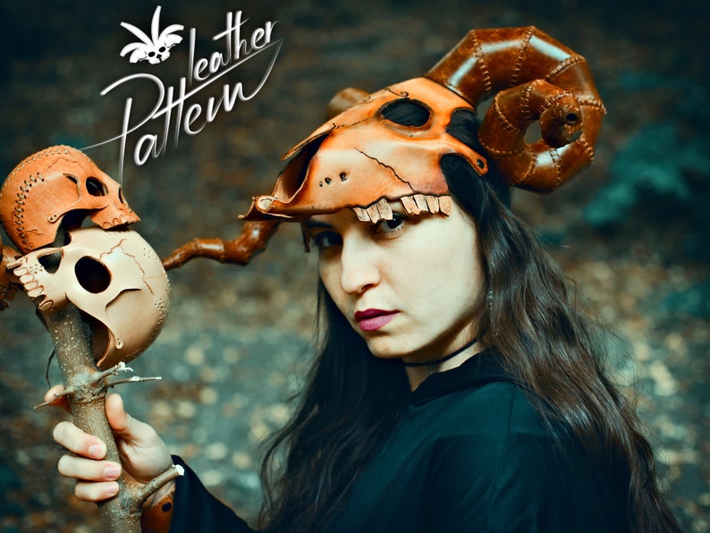 A cultist woman robed in black, wearing a horned animal skull mask made out of leather in the style of esoteric symbolism, dark orange and beige, imitating burnished bone and holding a staff adorned with human skulls made out of leather