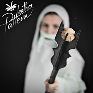 Puede incluir: Una maza de cuero negro con una parte superior esférica de color beige con costuras visibles. La maza tiene un diseño de cabeza dentada con múltiples puntas. El texto "Leather Pattern" es visible en la esquina superior izquierda en blanco.
