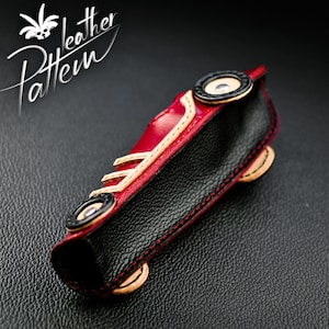 K&ouml;nnte beinhalten: Handgefertigte Ledertasche in Form eines Autos, mit rotem, schwarzem und beigem Leder. Die Tasche hat schwarze R&auml;der, rote N&auml;hte und den Text "Leather Pattern". Zum Aufbewahren kleiner Gegenst&auml;nde.