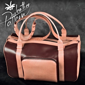 May include: A burgundy leather duffel bag with a pink leather trim and straps. The bag has a zipper closure and a small front pocket.