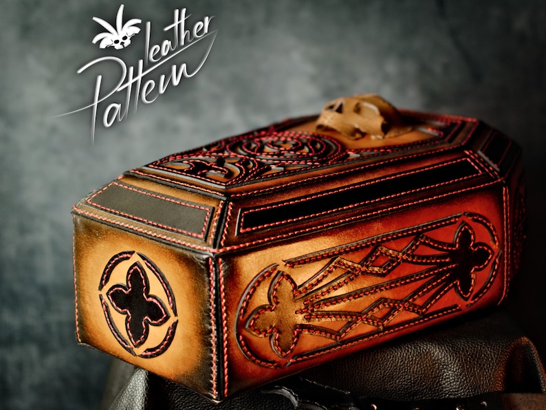 May include: A brown leather coffin-shaped box with intricate red stitching and a skull-shaped top. The box is decorated with a geometric pattern and has a black leather interior.