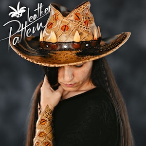 Könnte beinhalten: Ein beigefarbener Lederhut mit Krokodilleder-Struktur, verziert mit mehreren orangefarbenen Reptilienaugen und hervorstehenden weißen Zähnen entlang des dunkelbraunen Bandes. Der Text "Leather Pattern" ist oben links im Bild zu sehen.