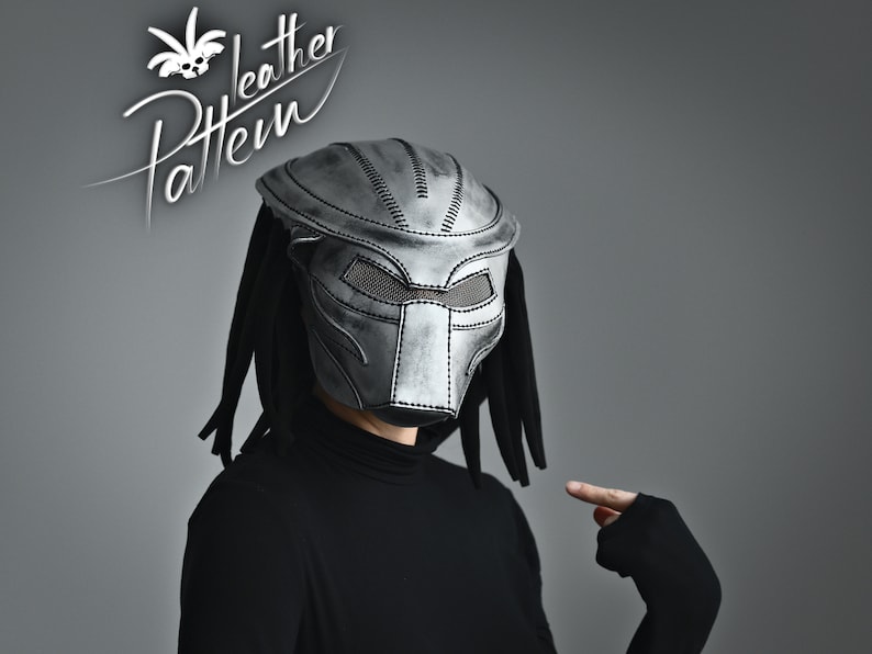 K&ouml;nnte beinhalten: Eine silberne Predator-Maske mit schwarzem Netzvisier und Dreadlocks. Die Maske ist aus Leder und hat ein gen&auml;htes Design.