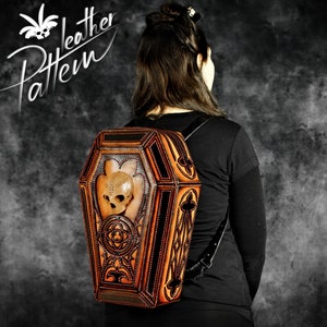 May include: A brown leather backpack shaped like a coffin with a skull design and metal accents. The backpack has a black strap and is being worn by a person.