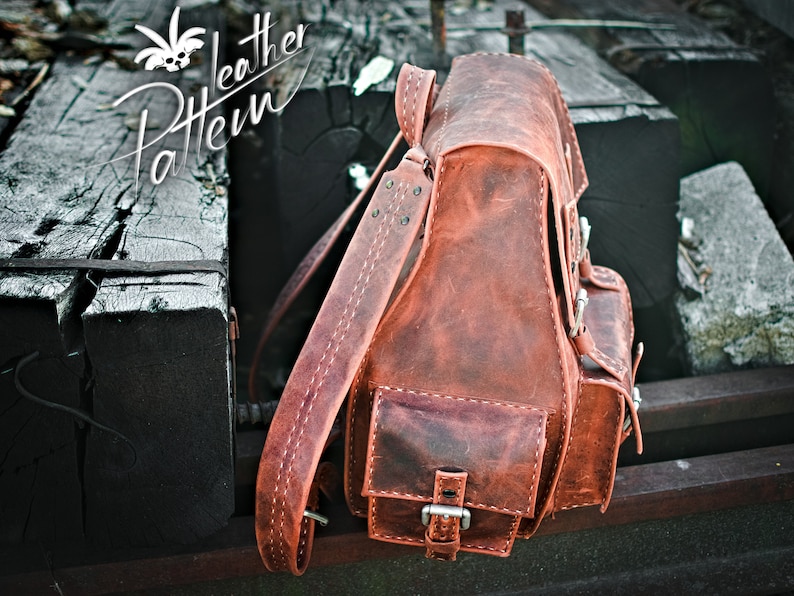 May include: A brown leather backpack with a flap closure and multiple pockets. The backpack has a distressed look and is made of high-quality leather.